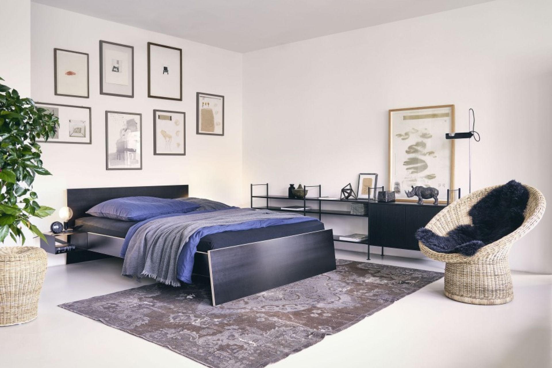 Schlafzimmer mit Stockholm Bett aus Birke Multiplex, ohne Kopfteil, mit blauer Bettwäsche und Teppich.